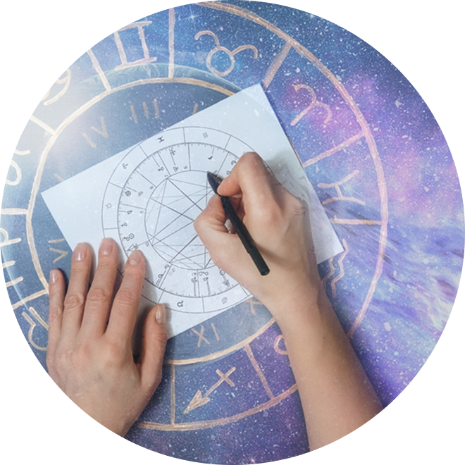 Close-up of hands drawing a natal chart on a paper overlaying a zodiac wheel background